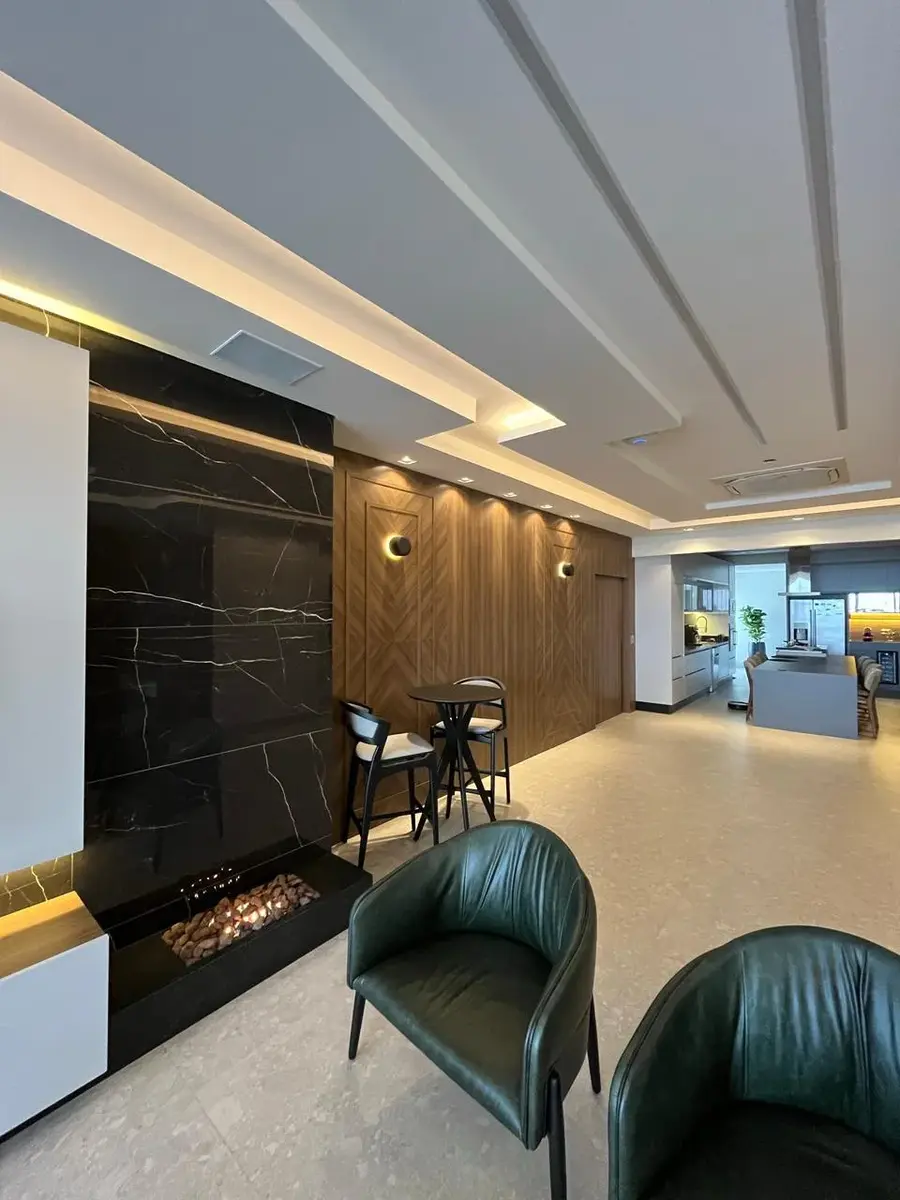 Sala planejada com painel em pedra escura e lareira